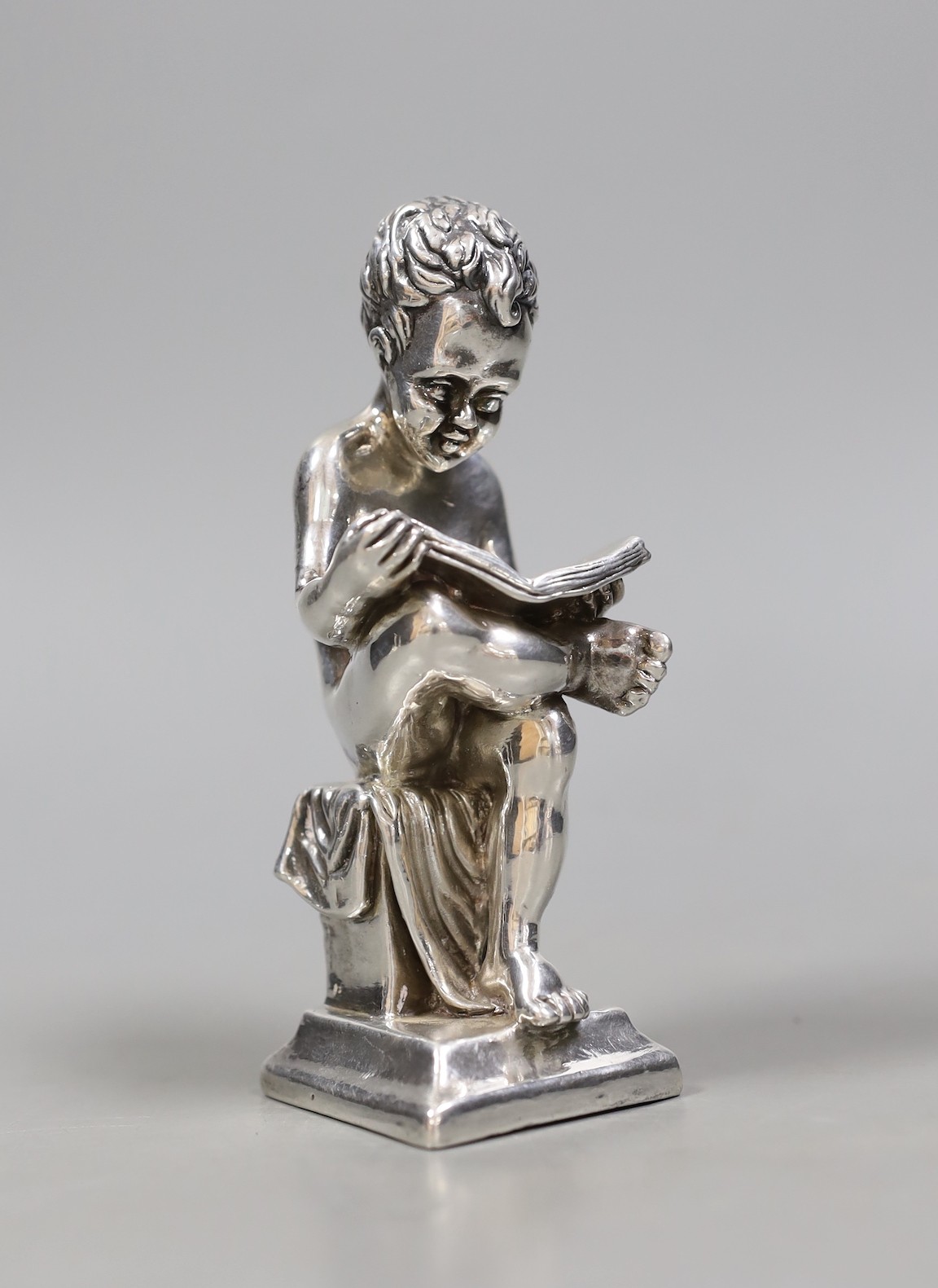 A modern Israeli sterling model of a seated young boy, reading, height 14.1cm.